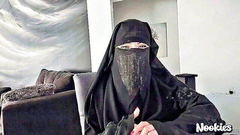 Arab woman in black niqab sitting on couch teasing seductively