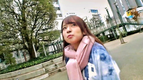Japanese woman with long brown hair in pink scarf, looking up in urban outdoor setting