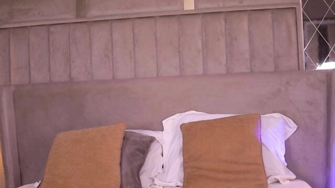 Luxurious upholstered bed headboard with plush orange pillows and white sheets ready for hot fucking