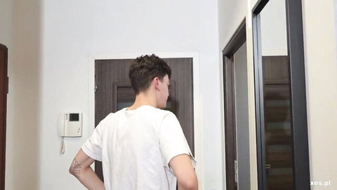 Tattooed young man in white t-shirt viewed from behind walking in hallway