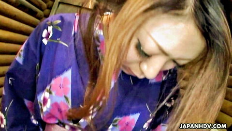 Japanese brunette in purple floral kimono gazing down intensely with seductive expression