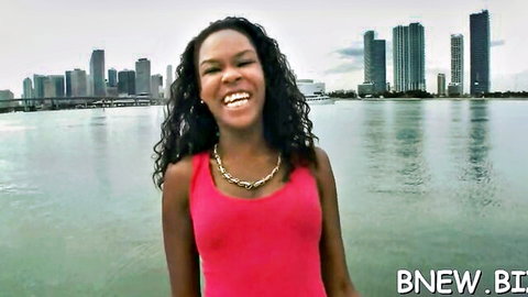 Tianna Love smiling in pink tank top by urban waterfront skyline