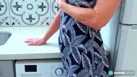 Elara in sexy leaf print dress, mature 50plus MILF kitchen pose