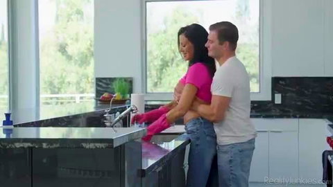 Reagan Foxx in pink crop top washing dishes, Nathan Bronson hugs from behind