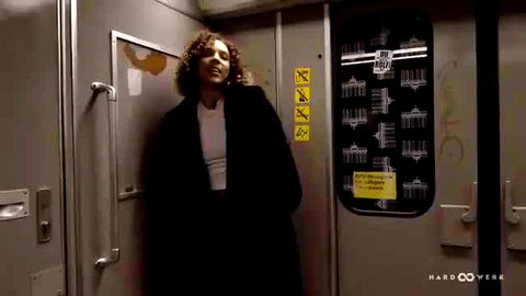 Curly-haired ebony beauty in open coat & crop top on subway train