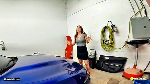 Brunette MILF in short skirt and low-cut blouse teasing cleavage next to blue sports car in garage