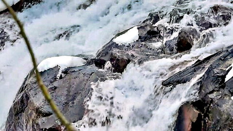 Rushing snowy waterfall cascading over rugged rocks in outdoor nature scene