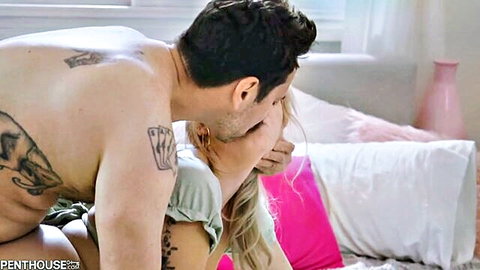Tattooed muscular man passionately kissing curvy blonde babe on bed
