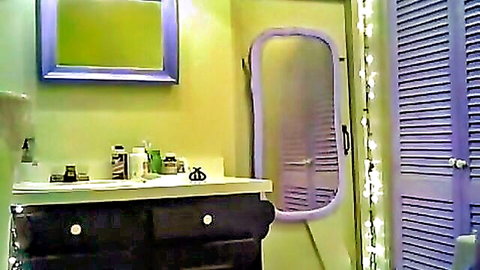 Colorful bathroom vanity with purple mirror and green walls in amateur setup