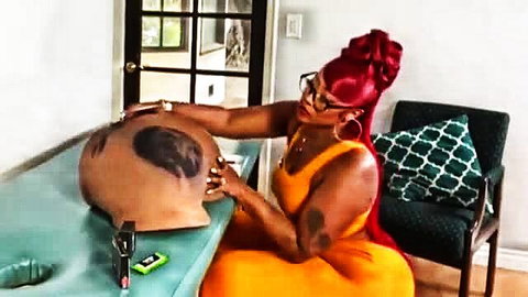 Cherokee D'Ass in tight orange dress, red hair updo, touching bald head BTS