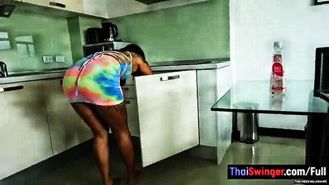 Thai woman in tie-dye outfit bending over in kitchen
