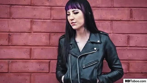 Casey Calvert in leather jacket against red brick wall