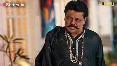 Mature Indian man in black kurta with beads necklace closeup
