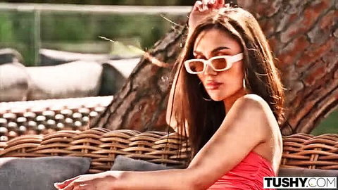 Brunette beauty in pink tube top and white sunglasses lounges seductively