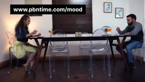 Brunette Indian woman in mini skirt chats with bearded man over drinks