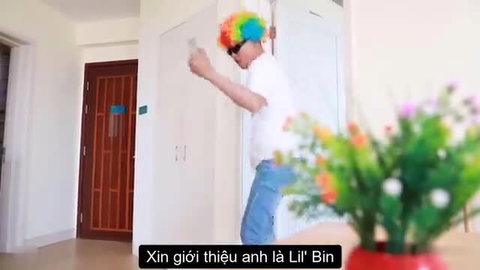 Vietnamese guy in clown wig and sunglasses dances silly in room