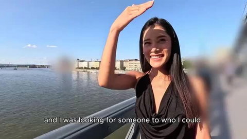 Colombian slut waving on balcony by river, smiling in sexy black dress