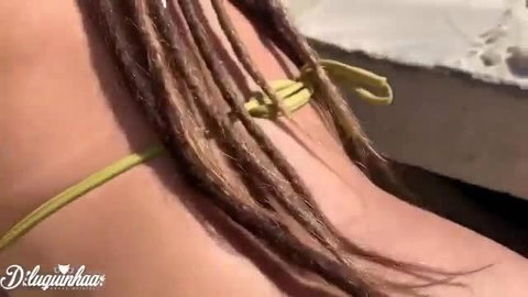 Teen with dreadlocks in yellow bikini top on beach
