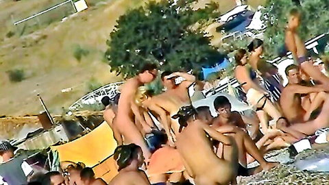 Nudist beach spy cam of sexy girl talking on phone near water with nude crowd