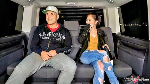 Sexy Asian babe in yellow top leather jacket ripped jeans sits close to hooded guy in van
