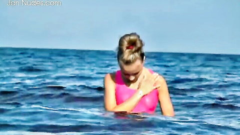 Ophelia relaxes in pink swimsuit after swimming on sunny beach