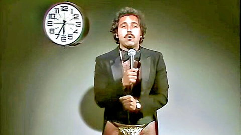 John Holmes in tuxedo performing with microphone, vintage adult film scene