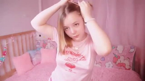 Cute tiny princess in strawberry shirt poses in pink bedroom