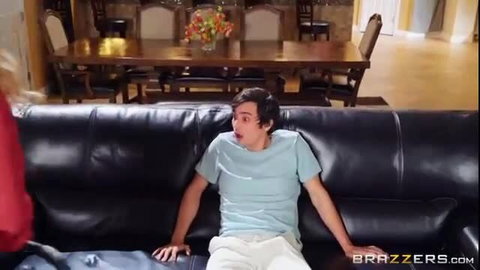 Shocked young man on couch as busty MILF shows off new boobs
