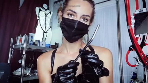 Mistress Euryale in black mask and latex gloves holds rod dominatrix tease