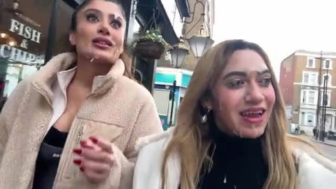 Two busty Middle Eastern women laughing outside fish & chips shop
