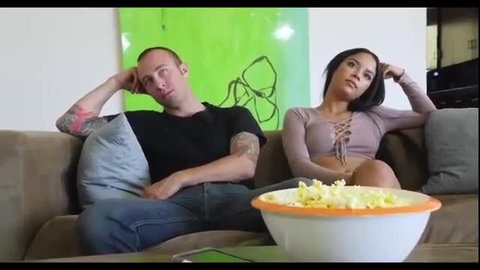 Tattooed guy and sexy Latina step-sis taunt on couch with popcorn