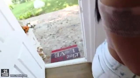 Cute black-haired teen at door with orange pumpkin toy, white tank top