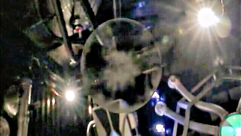 Futuristic sci-fi adult scene with glowing translucent sphere and metallic arms, dark lab setting