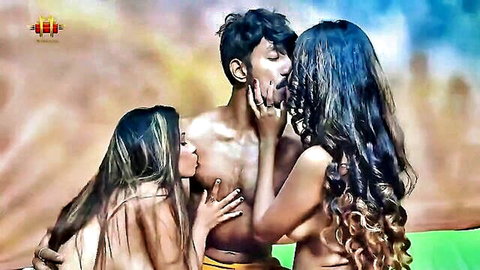 Two busty nude Indian brunettes kiss and grope muscular man's bare chest in steamy threesome.