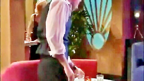 Man in vest serving drink to curvy redhead in elegant lounge