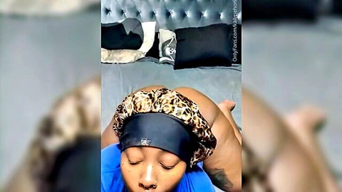 Ebony woman in leopard bonnet seductively posing in blue top