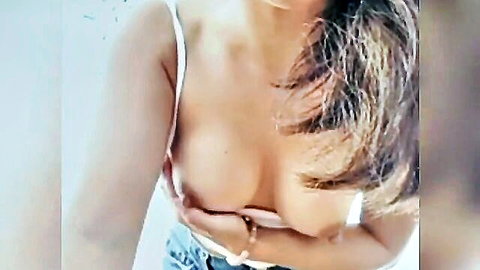 Chinese woman teasing cleavage in white tank top outdoors
