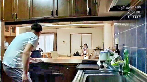 Japanese man at kitchen sink eyeing woman on sofa in casual home scene JAV