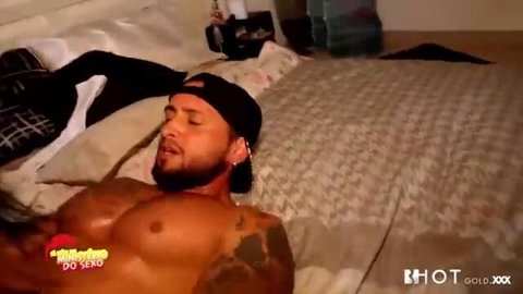 Muscular black man with tattoos lying shirtless on bed, HotGold