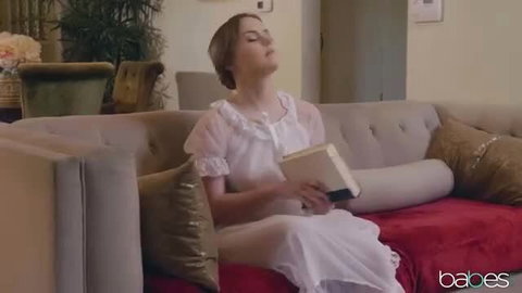 River Fox in sheer white nightgown reading on couch