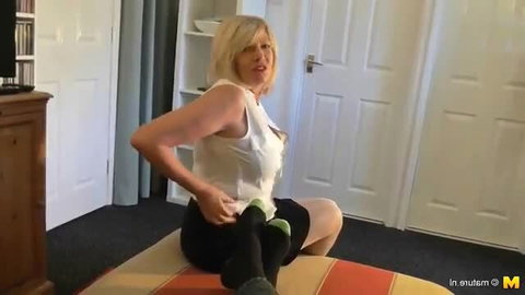Mature British homemaker Amy in white top and stockings on bed