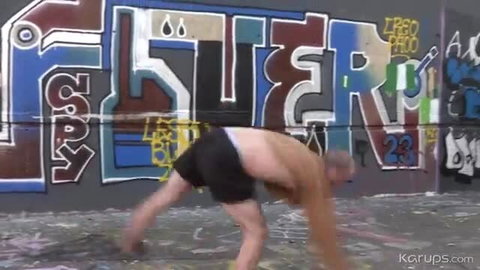 Nude man crawls by graffiti wall in wild outdoor tease
