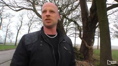 Bald German housewife Kelly smiling outdoors in leather jacket