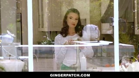 Curvy redhead ginger in white top and green pants posing in kitchen