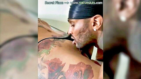 Ebony man with durag kissing tattooed ebony woman's back in intense foreplay.