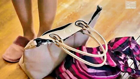 Sexy bare female legs in pink fuzzy slippers standing over dropped pink striped dress and beige handbag on wooden floor