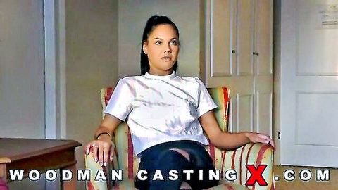 Tanned brunette teen in Woodman casting sits legs spread in tie-dye shirt and shorts