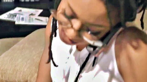 Ebony woman with dreadlocks and glasses in white tank top, smiling seductively