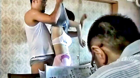 Asian woman in lingerie undressed by lover while husband reads nearby