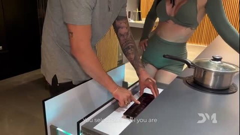 Iris Rodriguez in skimpy green bikini touches induction cooktop with tatted guy